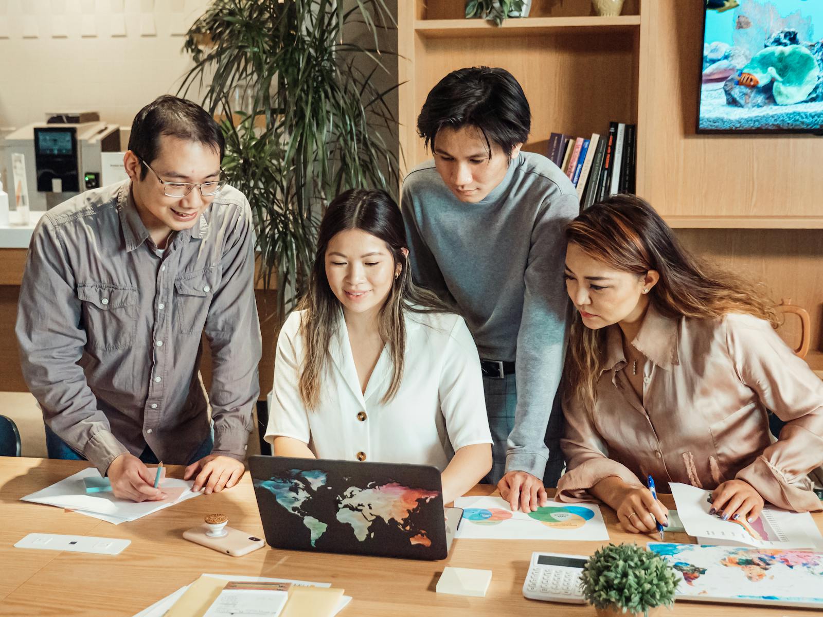 A diverse group of professionals collaborating over a laptop in a modern office setting.